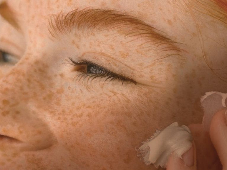 Le visage d'une jeune femme rousse appliquant une crème