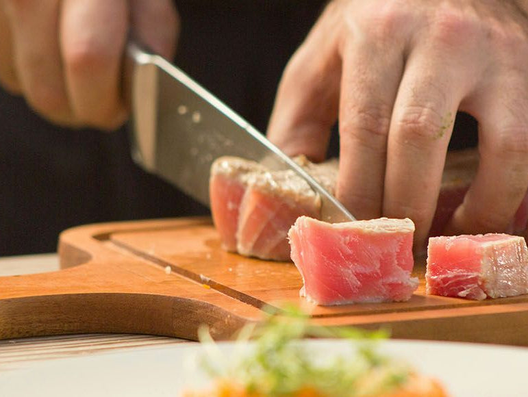 Un homme qui coupe du poisson sur une planche en bois