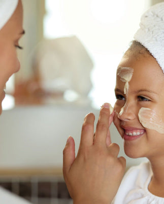 Une maman applique de la crème sur le visage de sa fille