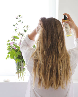 Femme de dos qui se met de la brume dans les cheveux