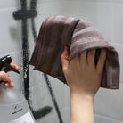 Microfibre spéciale pour le nettoyage des parois de douche et robinetteries. Personne nettoyant une vitre de douche avec la Microfibre salle de bain Body Nature.