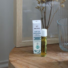 Roll-on relaxant aux huiles essentielles. Mise en scène : le roll on est posé sur une petite table à côté de son emballage.