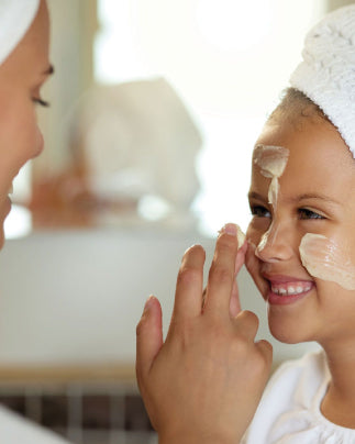 Une maman applique de la crème sur le visage de sa fille